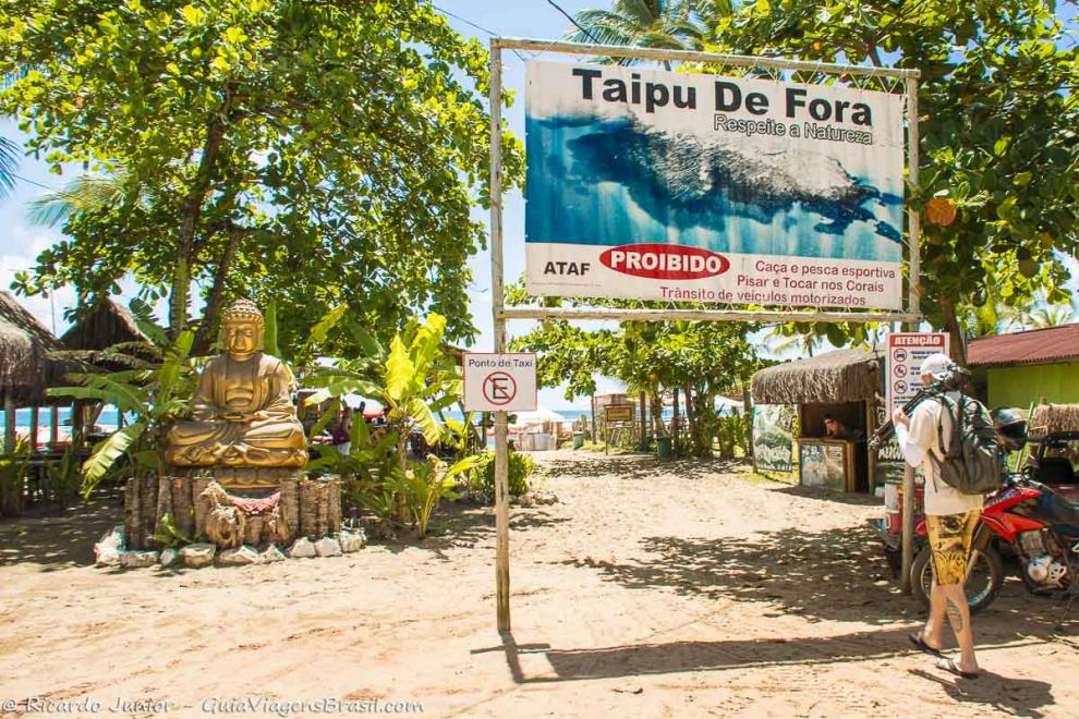 Imagem de um buda e placa indicando que é Praia Taipu de Fora.